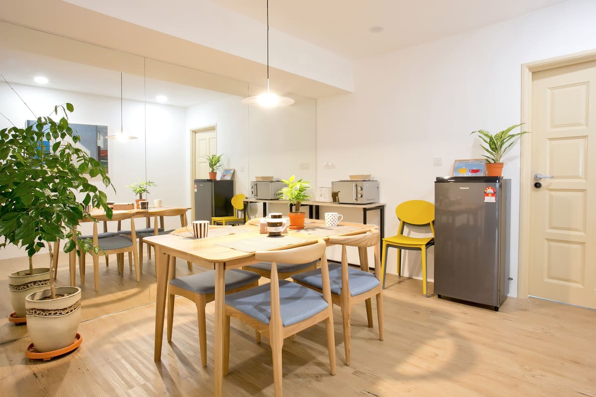 A modern kitchen with wooden furniture, a refrigerator, and potted plants.