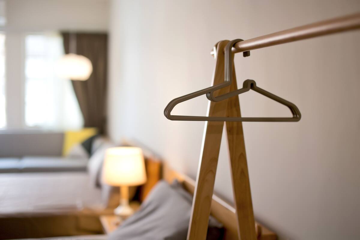 A wooden hanger on a bed frame in a hotel room.