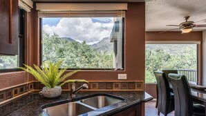 Une cuisine dotée d’un plan de travail en granit, d’un évier et d’une fenêtre offrant une vue sur les montagnes.