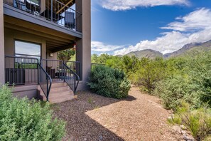 A modern building with a balcony, gravel pathway, and surrounding greenery.