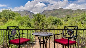 Un balcon avec deux chaises et une table, donnant sur un paysage montagneux.