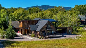 Une cabane en rondins dotée d’une grande terrasse et d’un espace salon extérieur abrité.