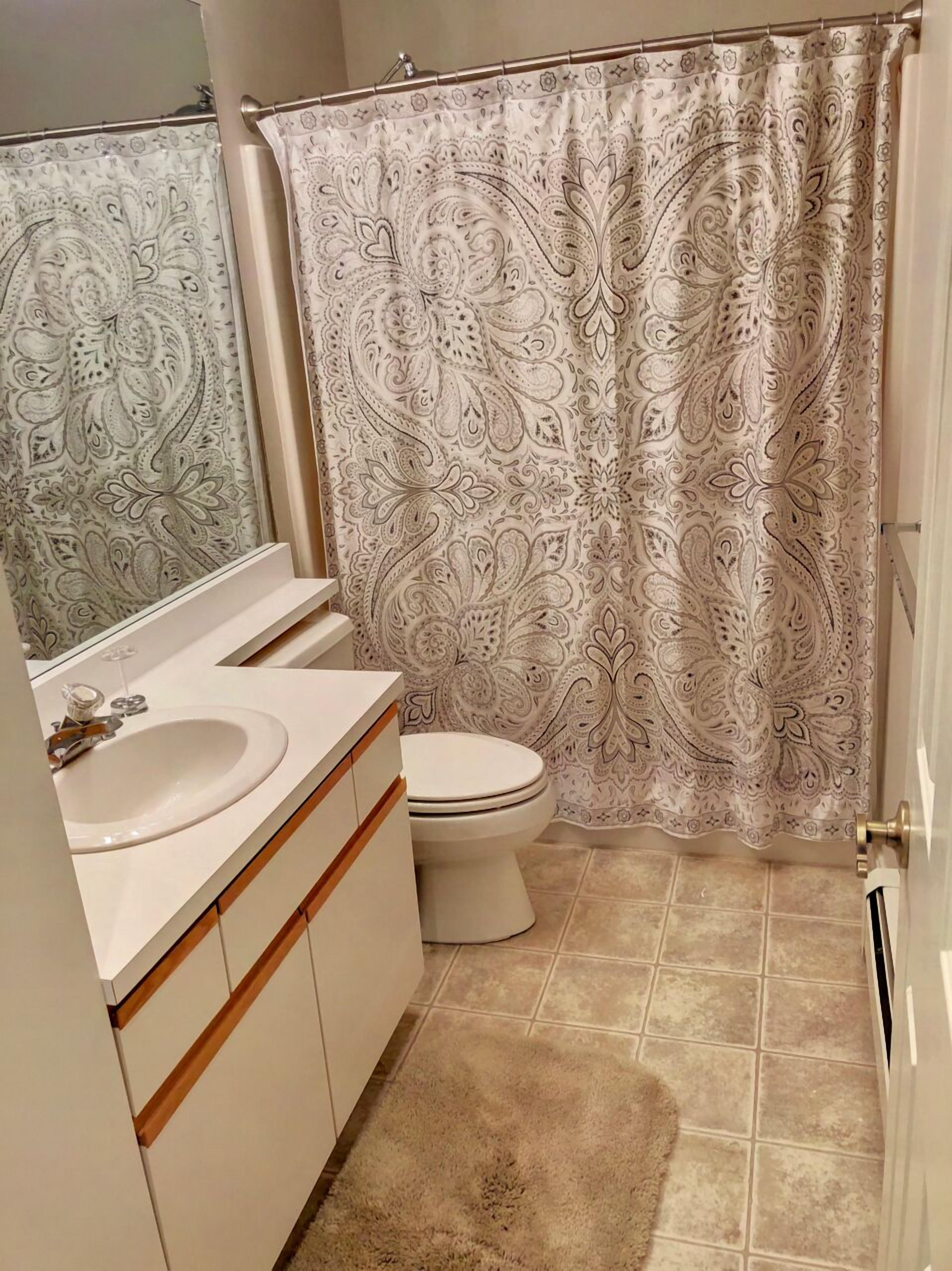 A bathroom with a toilet, sink, and mirror.