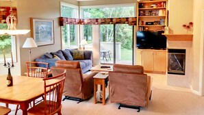 A cozy living room with a fireplace, a television, and a bookshelf. - F48 Modern home with AC within walking distance of golf course and Mt Washington Hotel (Bretton Woods)