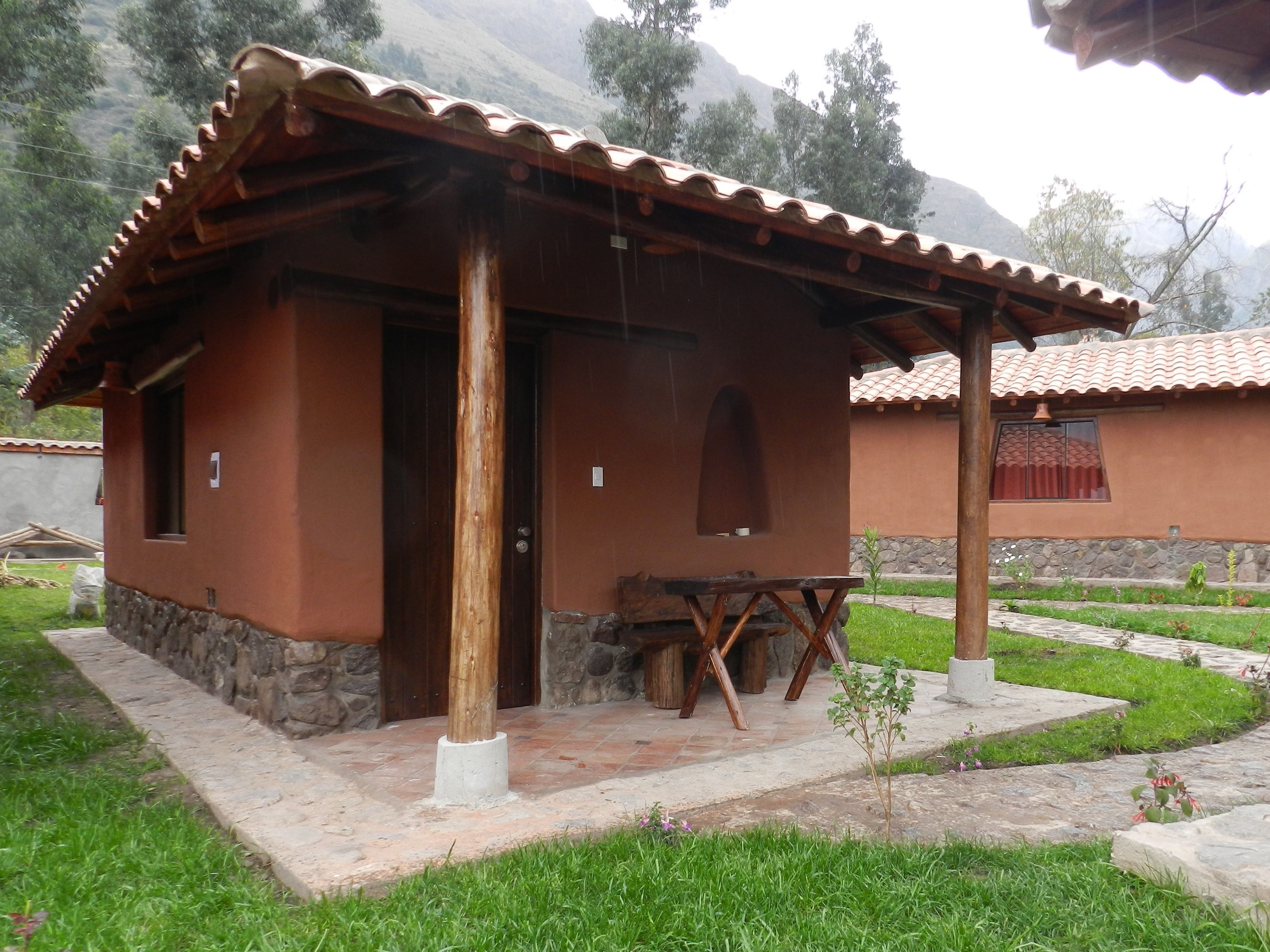 Un edificio rústico con techo de tejas, puerta de madera y una ventana pequeña.