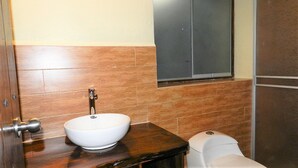 Un baño con lavamanos blanco, tocador de madera y un inodoro.