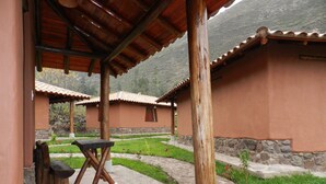 Un edificio rústico con un patio cubierto, muros de piedra y un camino de piedra que lleva a otro edificio.