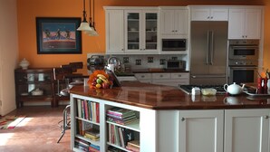 Een keuken met witte kasten, een houten eiland en een boekenplank vol boeken.