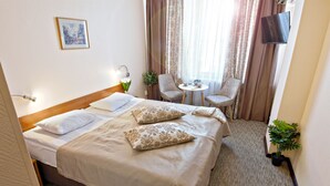 A hotel room with a bed, two chairs, a small table, a TV, and a potted plant. - Mini-Hotel Kievskiy (Kyiv)