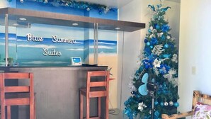 A reception area with a 'Blue Summer Suites' sign, a Christmas tree, and two wooden chairs.
