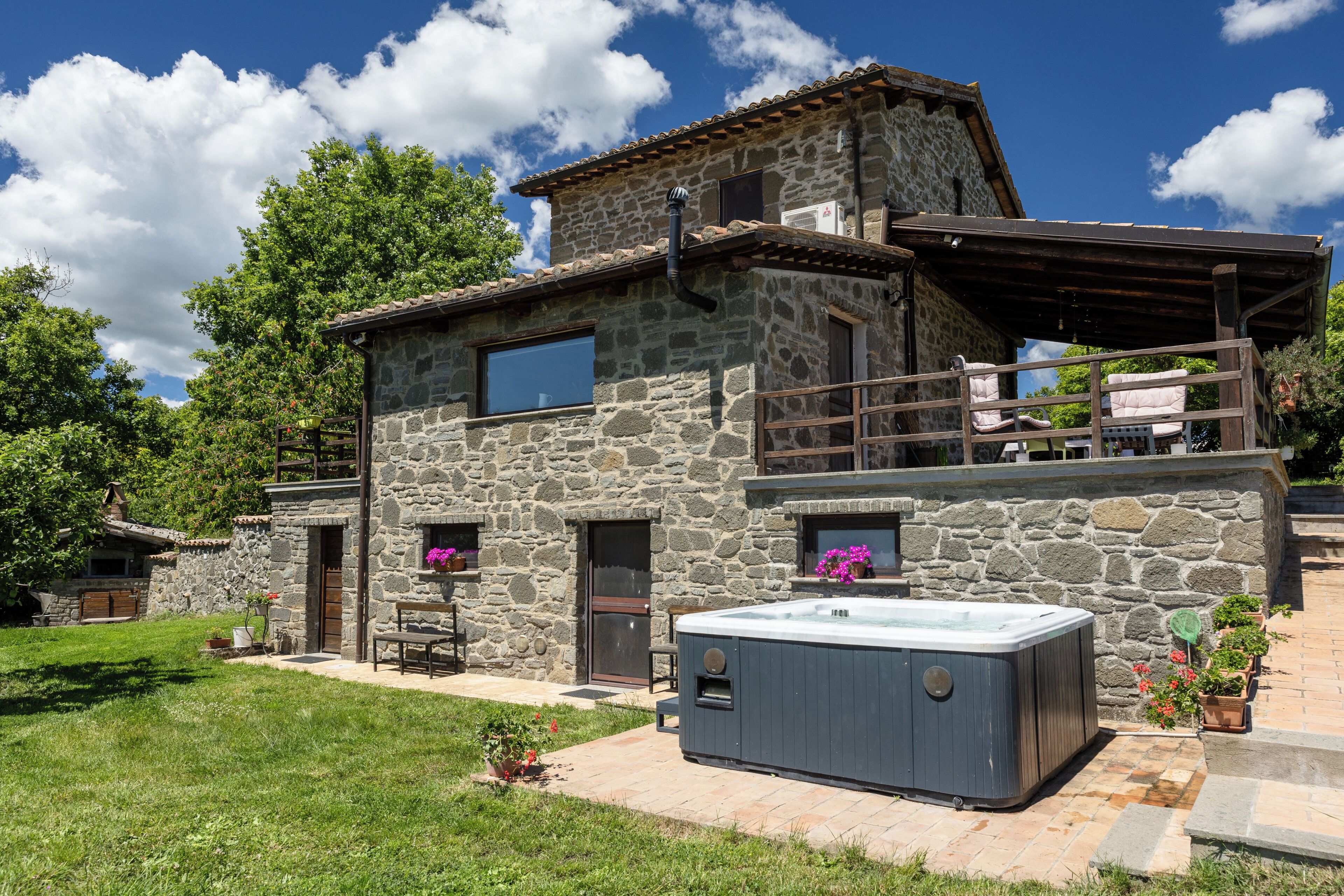 A stone building with a hot tub, outdoor seating, and a covered patio.