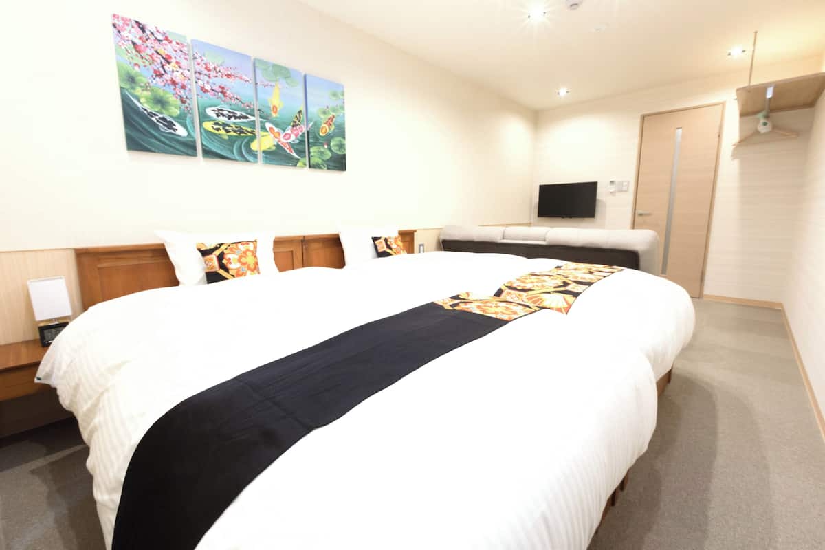 A hotel room with a large bed, a flat-screen TV mounted on the wall, and artwork above the bed.
