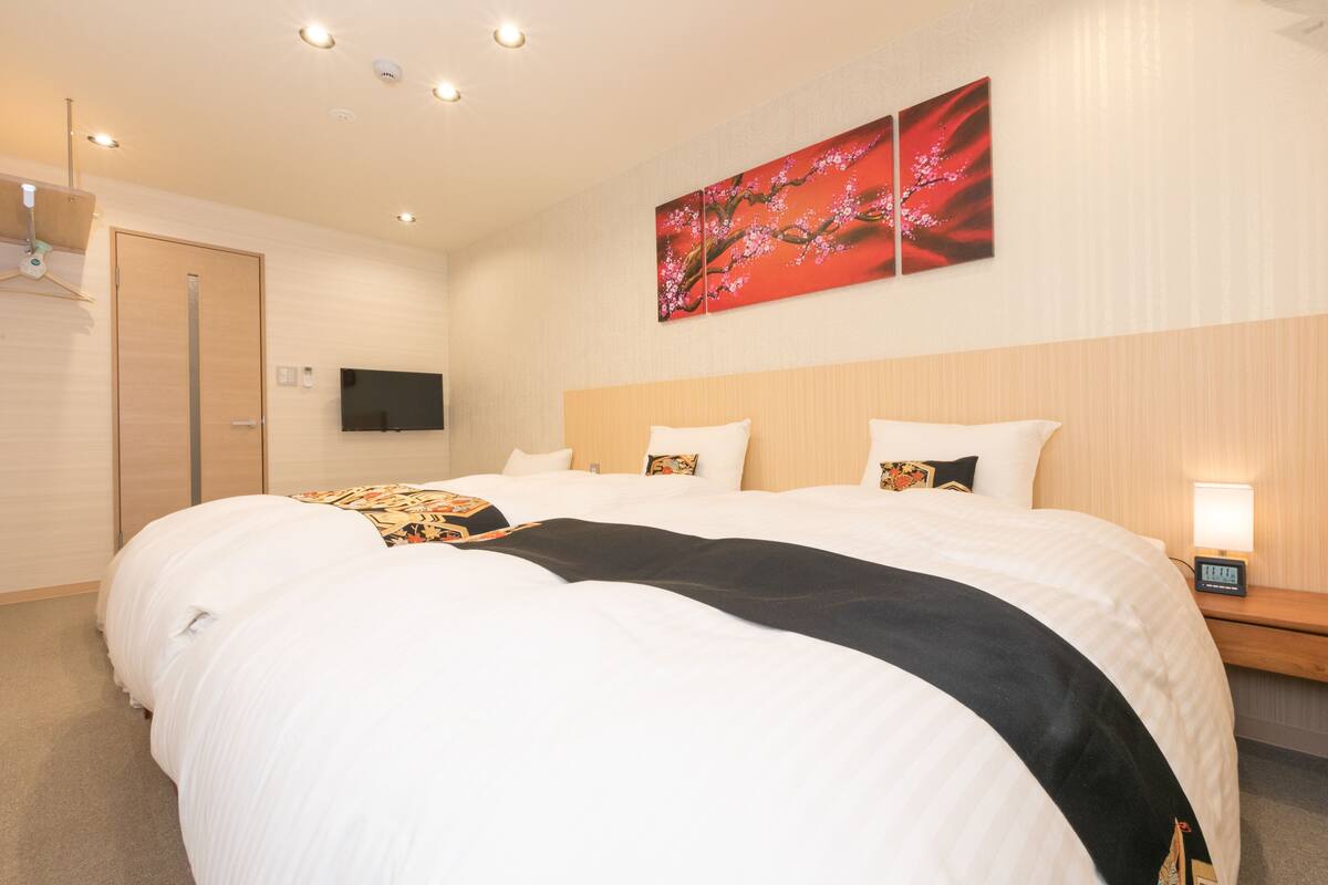 A hotel room with a large bed, a flat-screen TV, a wooden door, and a wall-mounted artwork.