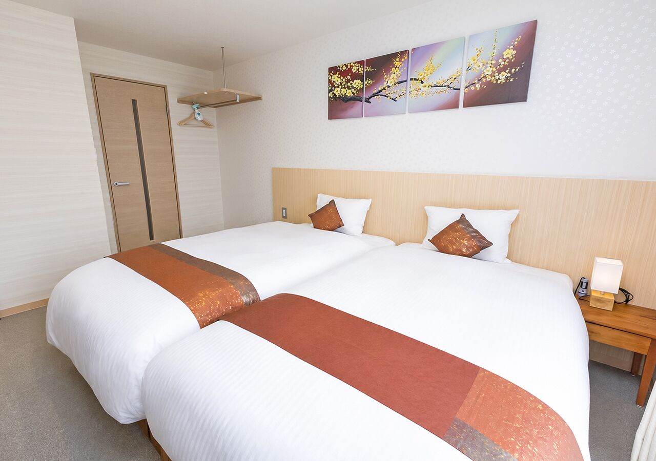 A hotel room with a large bed, a bedside table with a lamp, and artwork on the wall.