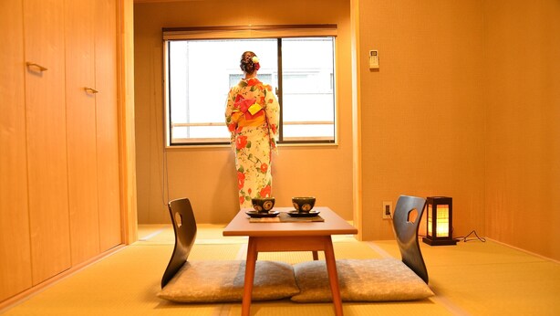 A traditional Japanese room with tatami flooring, a low table with two cups, and a person in a kimono. - Kamo-Zen (Kyoto)