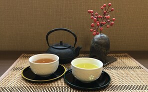 Two teacups on a woven mat, a black teapot, and a vase with red berries. - Kamo-Zen (Kyoto)