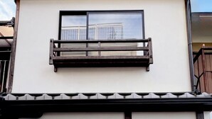A traditional Japanese building with a sliding wooden door, a small balcony, and a window. - Kamo-Zen (Kyoto)