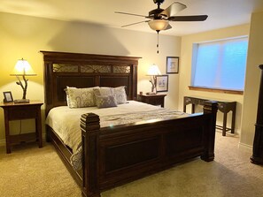 A bedroom with a wooden bed, two bedside tables with lamps, a ceiling fan, and a window with blinds. - Luxury Riverfront Home on 2 Acres, with Hot Tub, only minutes from downtown BV (Buena Vista)
