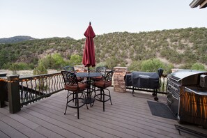 A deck with a table and chairs, a barbecue grill, and a view of a hilly landscape. - Luxury Riverfront Home on 2 Acres, with Hot Tub, only minutes from downtown BV (Buena Vista)