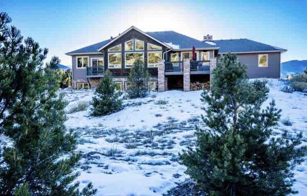 A large two-story house with a balcony, surrounded by snow-covered ground and trees. - Luxury Riverfront Home on 2 Acres, with Hot Tub, only minutes from downtown BV (Buena Vista)