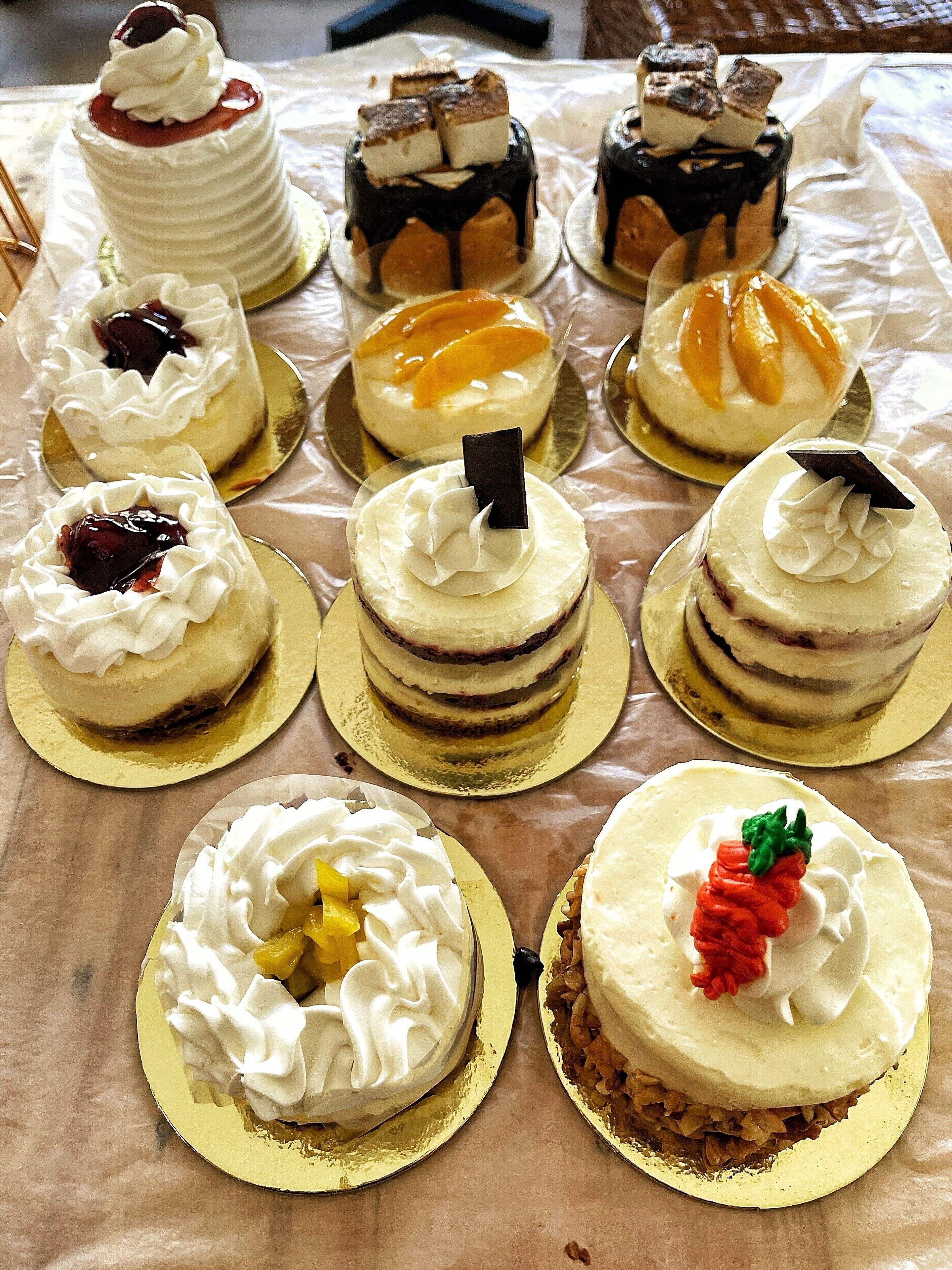 A variety of cakes on a table with a white tablecloth.