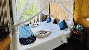 A bed with a canopy, a bedside table, and a view of greenery outside.