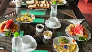 A dining table set with various dishes, including bread, fruit, and a hot beverage.