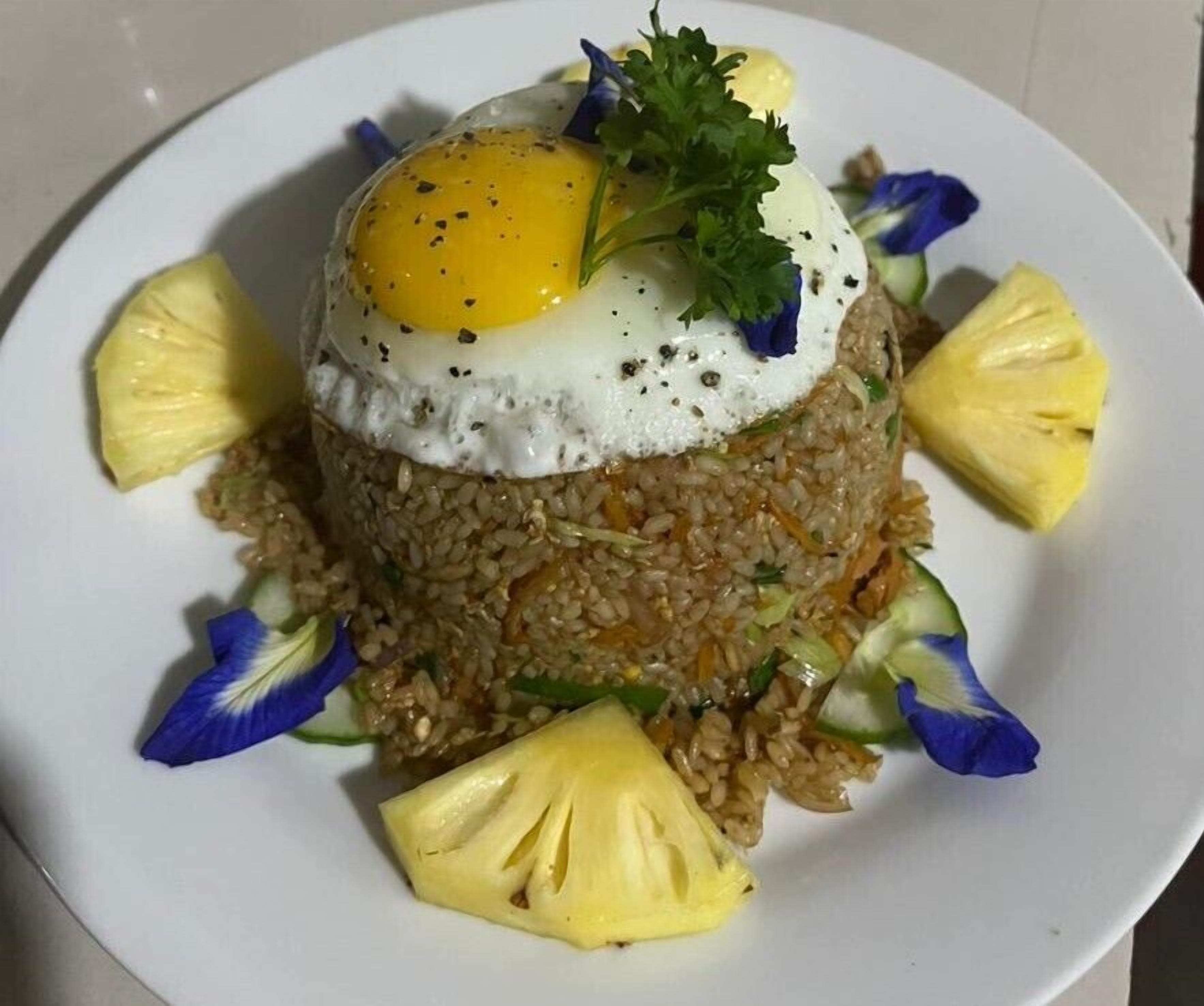 A plate of fried rice topped with a poached egg and garnished with parsley and blue flowers.