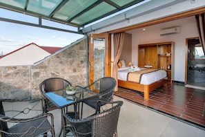 A balcony with wicker furniture and a bed in the adjacent room. - Hoi An Vi Khoa Villa (Da Nang)