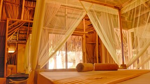 A room with a bed, a mosquito net, and a window with a view of trees. - Royal Beach Arugambay (Arugam Bay)