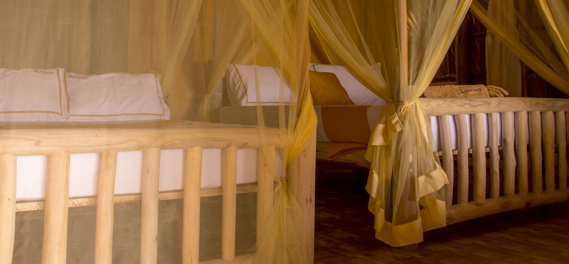 A room with two wooden beds, each with a canopy.