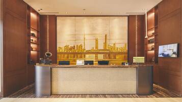 A reception desk with a cityscape mural, wooden paneling, and a flat-screen TV.