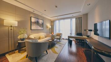 Una habitación de hotel moderna con sofá, sillón, escritorio y televisión.