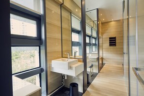Une salle de bain moderne avec une grande fenêtre, un lavabo blanc et un miroir.