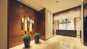 A modern lobby with wooden paneling, a reception desk, and two potted plants. - LJZ Supreme Tower Hotel(SHANGHAI New International Expo Centre) (Shanghai)