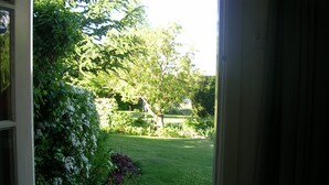 A garden view through an open door, featuring a lawn, various shrubs, and trees. - Alexandra Garden Court Motel (Alexandra)