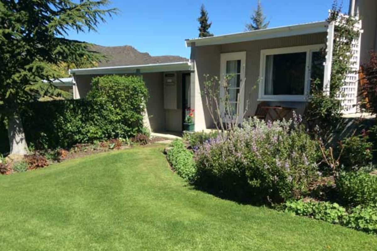 A house with a well-maintained lawn, a front door, and a small porch area.