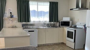 A compact kitchen with a microwave, stove, and sink. A small refrigerator is also visible. - Alexandra Garden Court Motel (Alexandra)