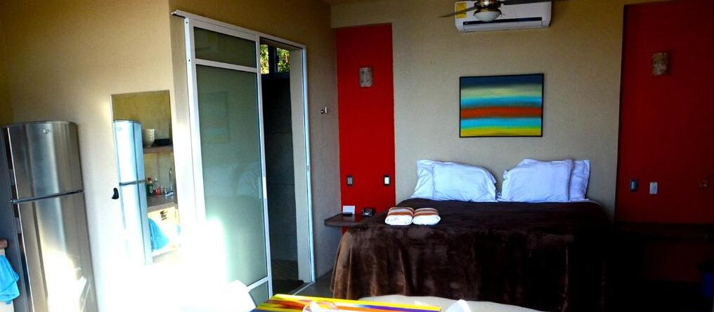 Ein Schlafzimmer mit Bett, Kleiderschrank, Spiegel und Deckenventilator.