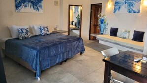 Habitación de hotel con cama, escritorio y zona de estar con banqueta.