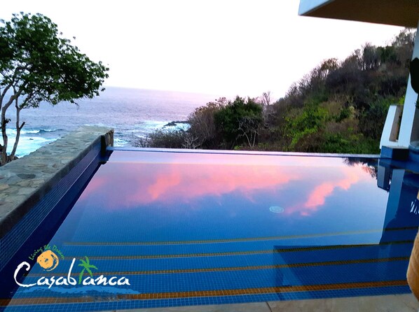 Une piscine à débordement offrant une vue sur l’océan et un magnifique coucher de soleil.