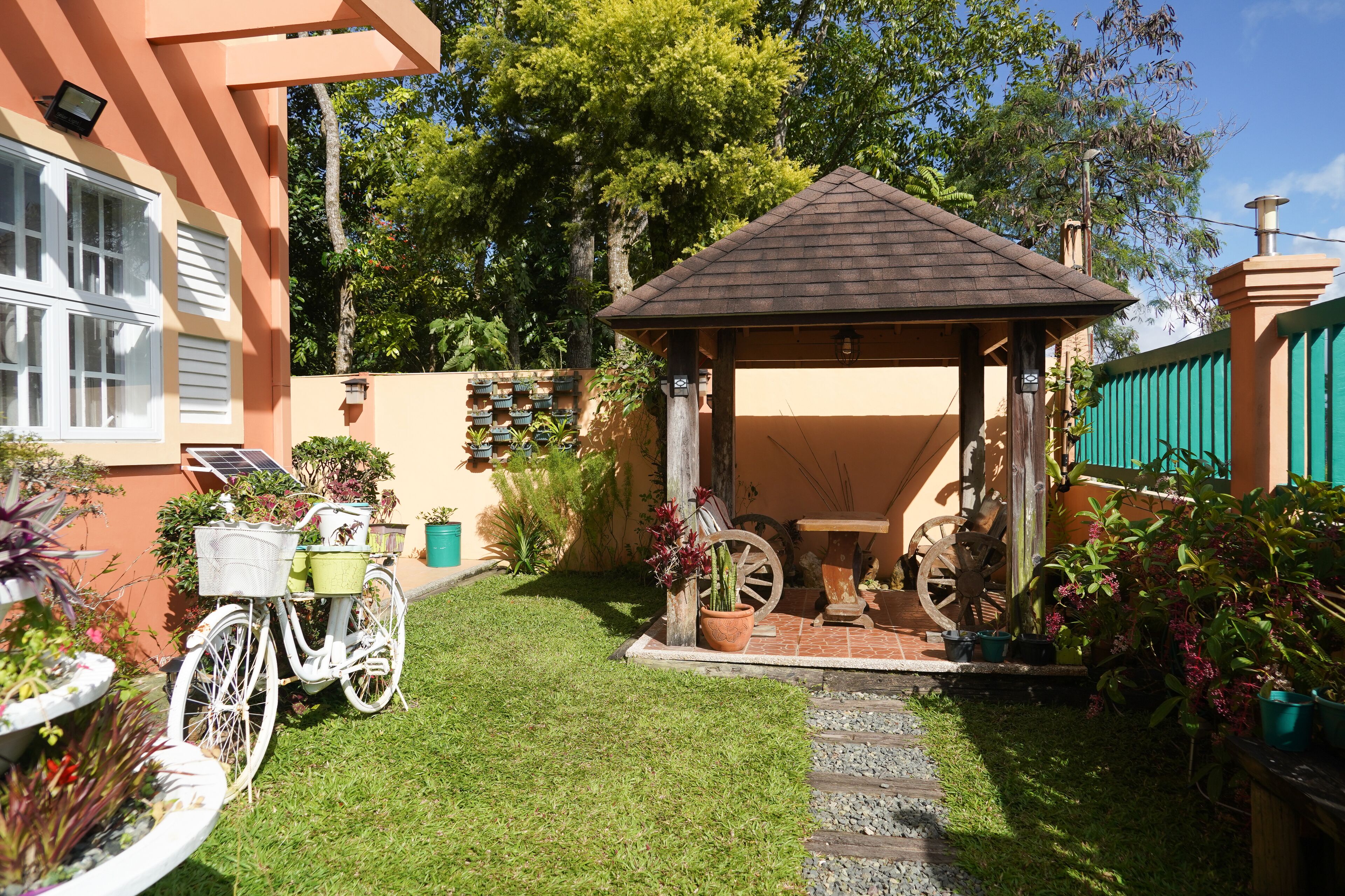 Un jardin agrémenté d’un kiosque, d’un vélo et de plantes en pot.