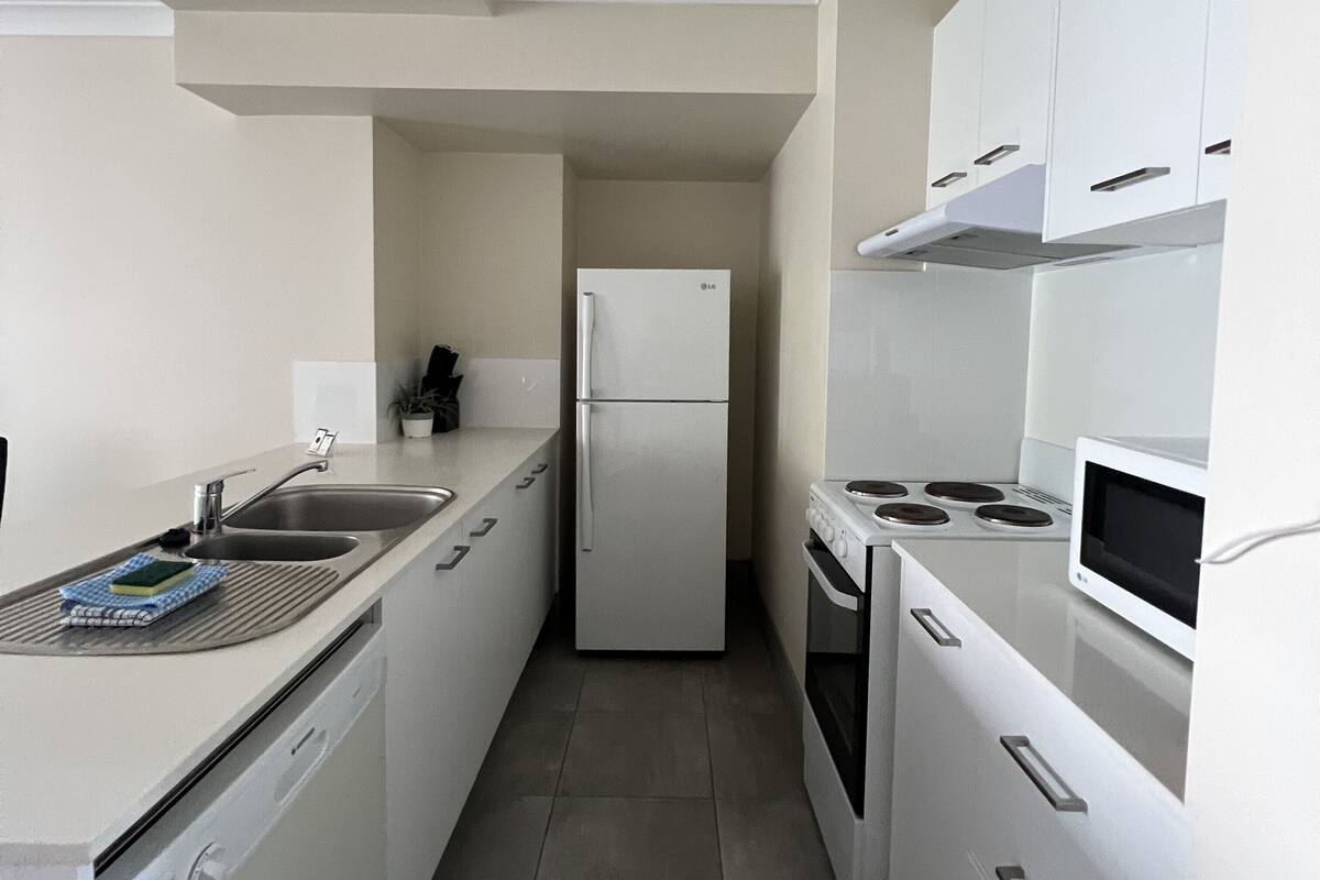 Una cocina moderna con electrodomésticos blancos, incluyendo un refrigerador, estufa y microondas.