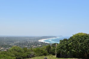A coastal landscape with a beach, greenery, and a clear sky. - Gamboozini Lodge (Ponta d'Ouro)