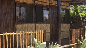 Un edificio rústico de madera con ventanas amplias y una valla de bambú.