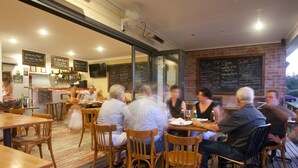 A restaurant with wooden tables and chairs, a chalkboard menu, and a bar area. - Vacy Hunter Valley Lodge (Vacy)