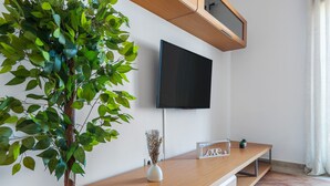 A modern living room with a flat-screen TV, a wooden console table, a potted plant, and a small decorative item. - Playa Grande PLUS - Punta del Moral Beach PPHG207P209 (Punta del Moral)