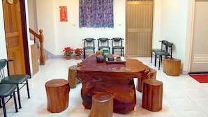 A dining area with a large wooden table surrounded by chairs, a staircase, and a door with a number sign. - Tophome 9 (New Taipei City)