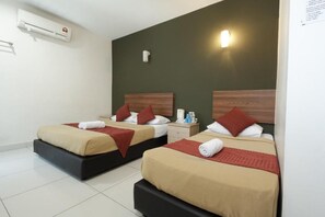 A hotel room with two beds, each with a wooden headboard, beige bedding, and red throw pillows. There is a nightstand with a lamp and toiletries, and an air conditioning unit on the wall. - COOP Hotel Putrajaya & Cyberjaya (Dengkil)