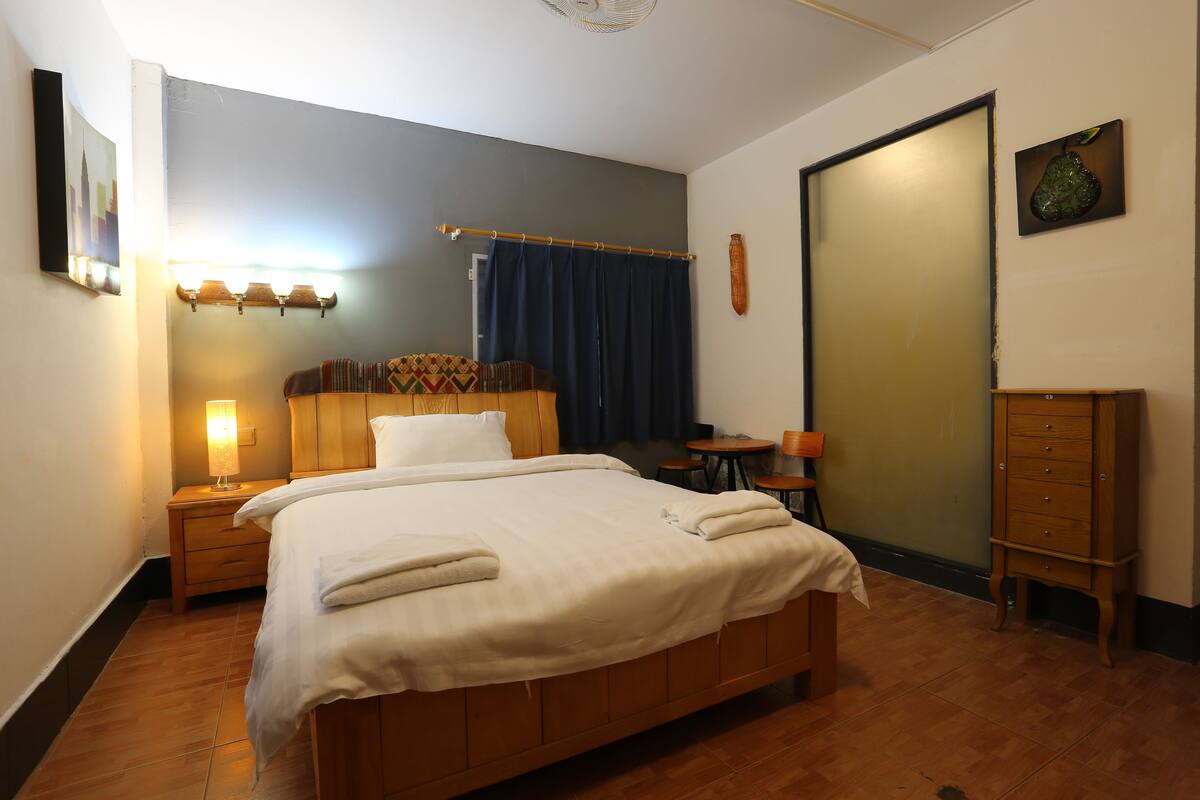 Una camera da letto ordinata con un letto grande, comodini, un tavolino e un armadio.